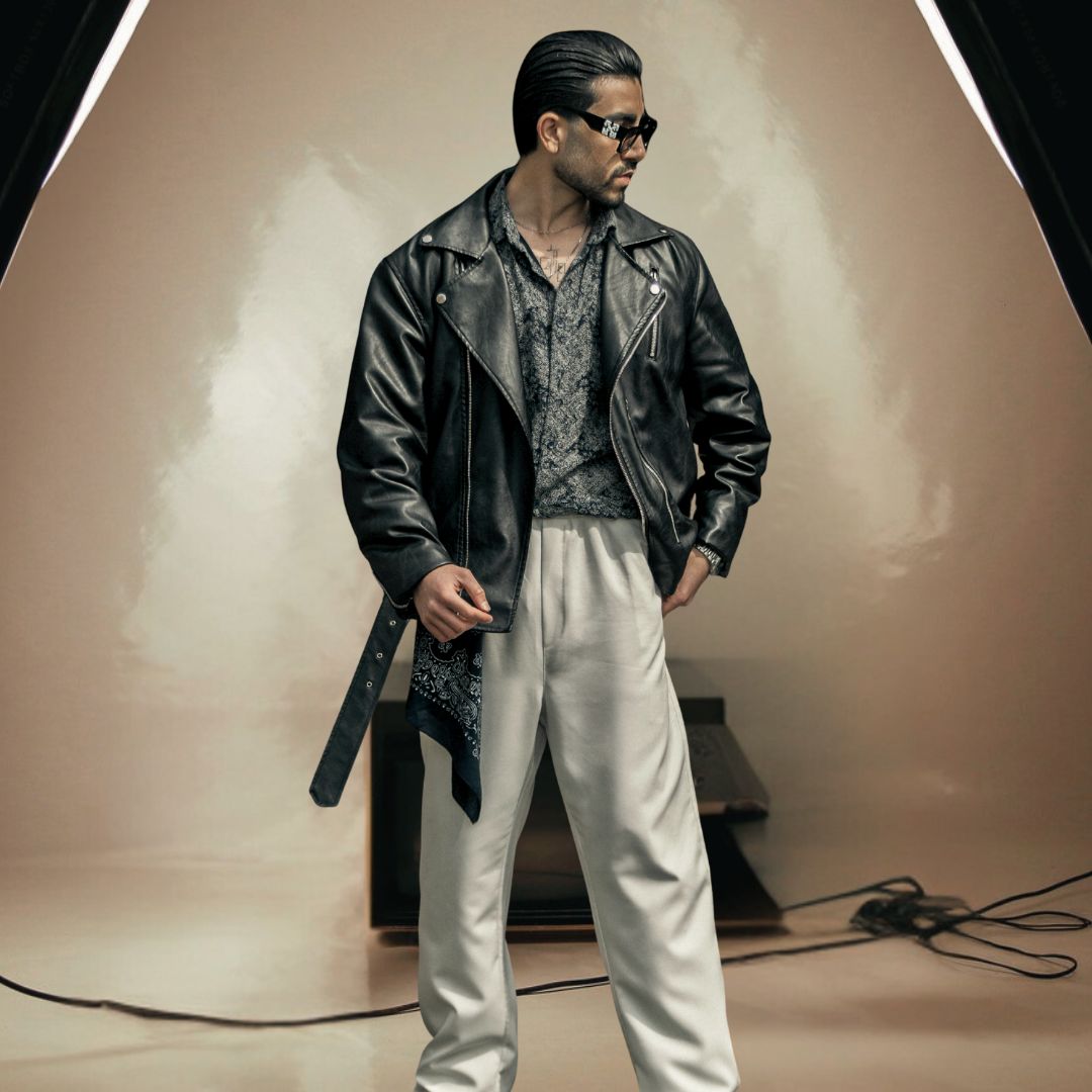 Man wearing a black leather jacket and sunglasses in a studio setting